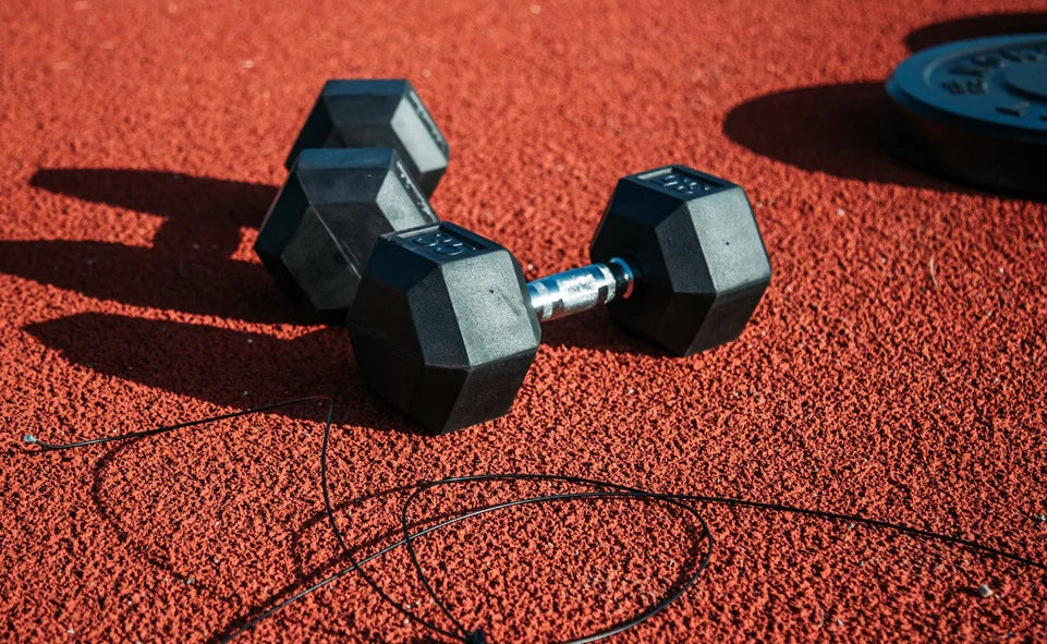 Two black dumbbells on a red textured surface with a thin black wire.